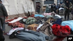 Syrians stand near the bodies of those killed by Syrian government airstrike outside a field hospital, Aleppo, Dec. 16, 2013.