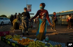Street vendors, wearing face masks as a precaution against the spread of the new coronavirus, sell fruit on the street corner in Katlehong, east of Johannesburg, South Africa, May 6, 2020.