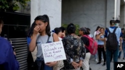 Una mujer sostiene un cartel mientras hace fila con otras personas afuera del ministerio de Capital Humano. Exigen ser atendidas por la ministra Sandra Pettovello, en Buenos Aires, Argentina, el lunes 5 de febrero de 2024.