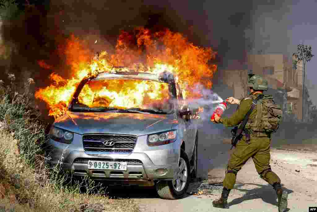 이스라엘 점령 지역 서안지구의 아크라바에서 팔레스타인인 차량에 붙은 불을 이스라엘군이 끄고 있다. 이 차량은버스 정류장에서 총격을 가할 때 이용된 것으로 알려졌다. 