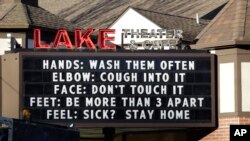FILE - In this photo taken March 17, 2020, a marquee outside the Lake Theater & Cafe in downtown Lake Oswego, Oregon, encourages people to practice social distancing and stay home if sick.