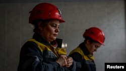 Nataliia, 43-years-old, and Krystyna, 22-years-old, dress in uniforms before going down to work their shift underground, amid Russia's attack on Ukraine, at a mine in Dnipropetrovsk region, Ukraine on November 17, 2023. (REUTERS/Alina Smutko)