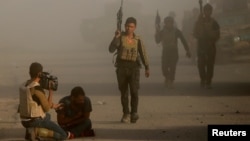 An Iraqi journalist springs into action after an Islamic State suicide bomber attacked an Iraqi special forces unit with a car bomb during clashes in Bartella, east of Mosul, Iraq, Oct. 20, 2016.