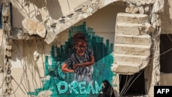 A woman sits on the broken steps of a partially-collapsed building in Gaza City destroyed by bombardment during the May 2021 conflict between Hamas and Israel.