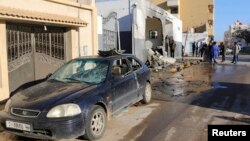 Civilians and security personnel stand at the scene of an explosion at a police station in the Libyan capital Tripoli, March 12, 2015.