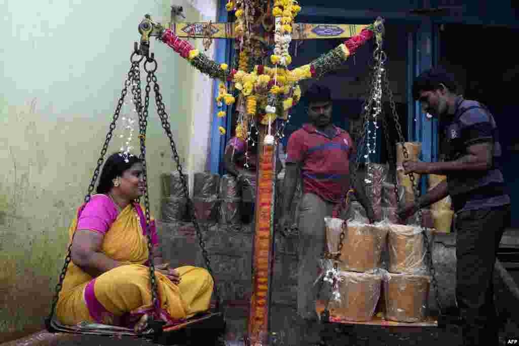 A Hindu devotee sits on a scale to buy her weight in jaggery as an offering to goddesses during the Sammakka Saralamma Jatara festival, in Hyderabad, India.