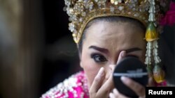 A Thai classical dancer touches up her makeup before performing at the Erawan shrine, site of Monday's deadly blast, in Bangkok, Aug. 21, 2015. Thai tour operators fear the unsolved attack will deter visitors.