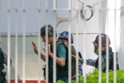 FILE - Japanese journalist Yuki Kitazumi raises his hands as he is escorted by police upon arrival at the Myaynigone police station in Sanchaung township in Yangon, Myanmar, Feb. 26, 2021.