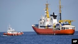 Kapal Penjaga Pantai Italia (kiri) mendekati kapal Aquarius milik LSM Perancis NGO "SOS Mediterranee" di Laut Tengah, 12 Juni 2018.