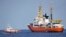 An Italian Coast Guard boat, left, approaches the French NGO "SOS Mediterranee" Aquarius ship, in the Mediterranean Sea, June 12, 2018. Italy dispatched two ships Tuesday to help take 629 migrants stuck off its shores on the days-long voyage to Spain.