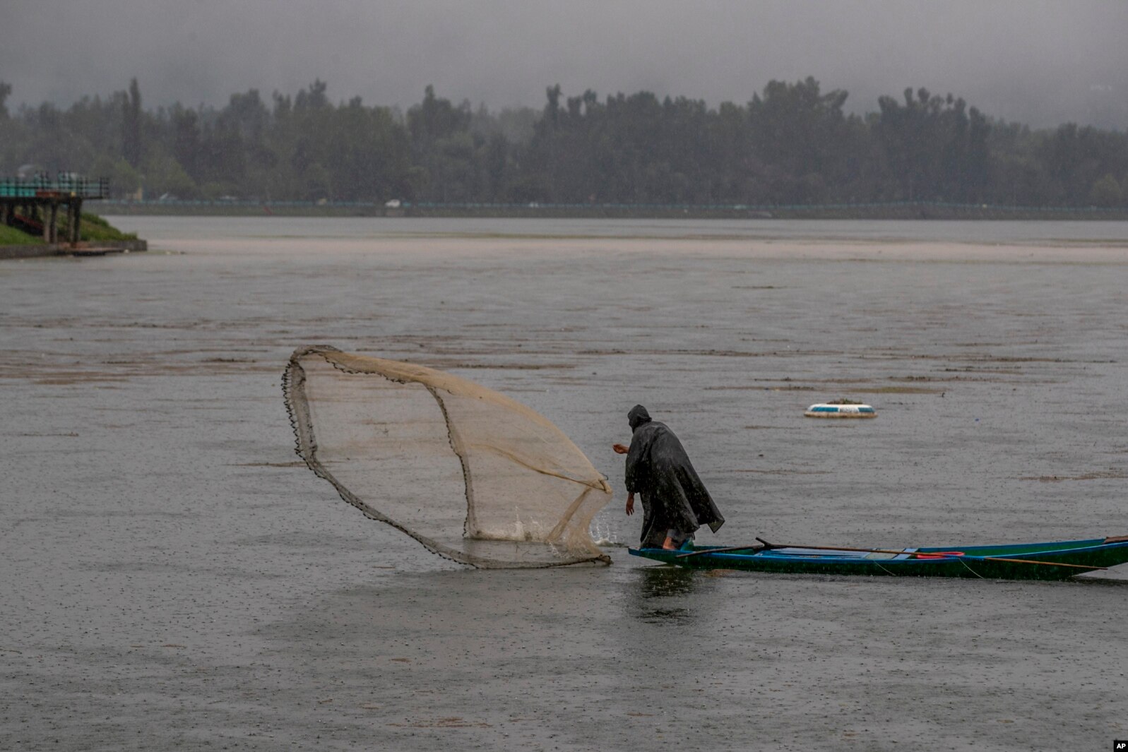 A Kashmiri fisherman casts his net as it rains at the Dal Lake on the outskirts of Srinagar, Indian-controlled Kashmir.