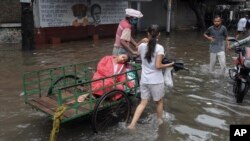 A sick person is taken on a cycle cart to a doctor in a waterlogged street following heavy rains in Kolkata, India.