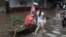 A sick person is taken on a cycle cart to a doctor in a waterlogged street following heavy rains in Kolkata, India.