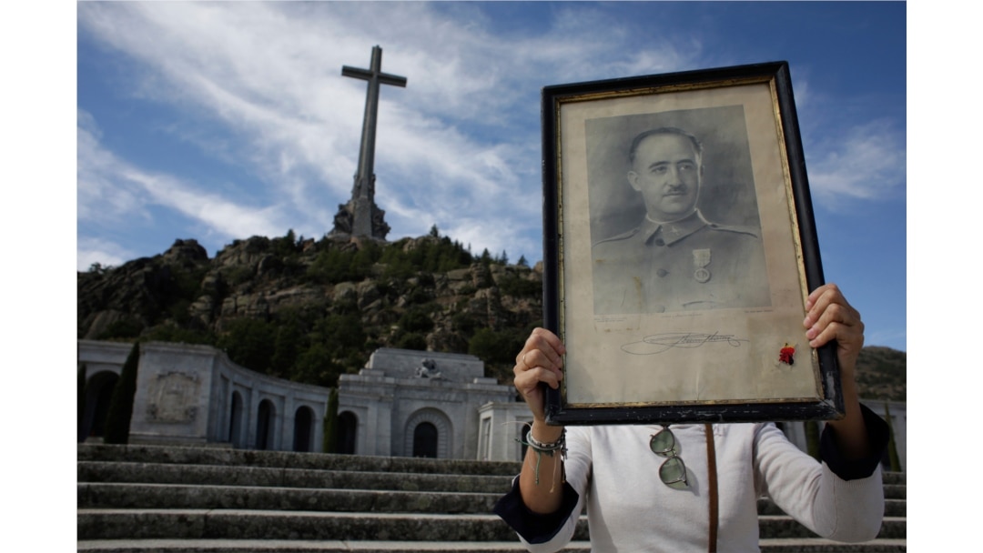 A visitors holds a portrait of former Spanish dictator Francisco Franco at the Valley of the Fallen mausoleum near El Escorial, outskirts of Madrid, Spain, Oct. 4, 2019.