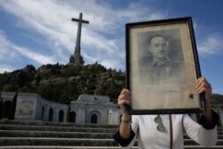 A visitors holds a portrait of former Spanish dictator Francisco Franco at the Valley of the Fallen mausoleum near El Escorial, outskirts of Madrid, Spain, Oct. 4, 2019.