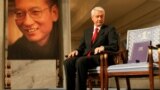 Chairman of the Norwegian Nobel Committee Thorbjoern Jagland looks down at the Nobel certificate and medal on the empty chair where this year's Nobel Peace Prize winner jailed Chinese dissident Liu Xiaobo would have sat, as a portrait of Liu is seen in th