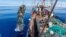 FILE - Garbage, much of it plastic, from the Great Pacific Garbage Patch between California and Hawaii is being lifted onto a cargo sailing ship by the Ocean Voyages Institute, which works to clean up trash in the ocean. 