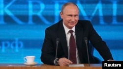 Russian President Vladimir Putin smiles as he takes part in a televised news conference in Moscow, Dec. 19, 2013.