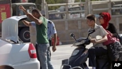 A police office checks the trunk of a car of an ethnic Uighur man as security forces are deployed at a square in Kashgar in China's western Xinjiang region, August 2, 2011.