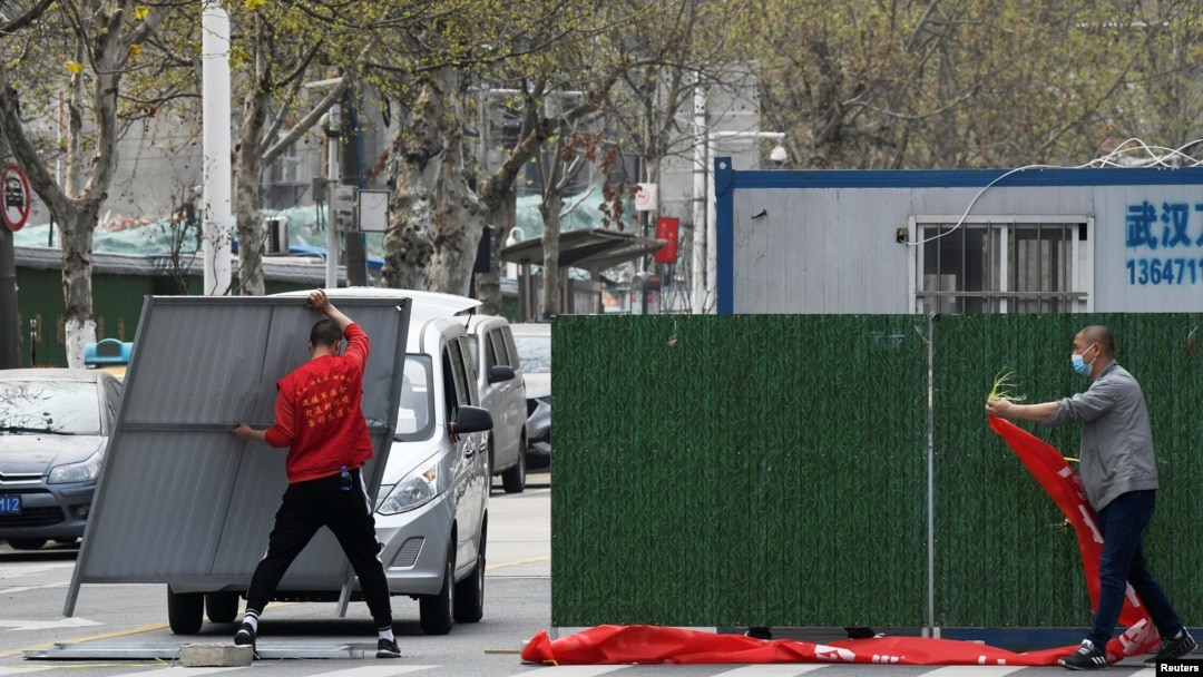 Para petugas mengenakan masker saat membuka kembali sebuah jalan di Wuhan, China yang semula diblokir untuk menghambat perebakan virus corona, 21 Maret 2020.