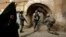 FILE - An Iraqi woman passes U.S. troops and Iraqi police officers as they stand guard in the Bab al-Jadeed area of Mosul, 360 kilometers (225 miles) northwest of Baghdad, Iraq.