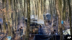 Migrants make shelters from plastic sheets and tree branches at a makeshift camp in a forest outside Velika Kladusa, Bosnia, Jan. 5, 2021. 