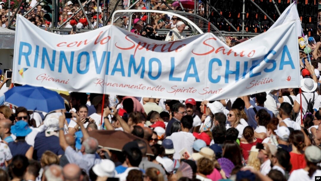 Pope Francis is driven through the crowd as a large banner reading "Let's renew the church" is visible in the foreground, in Palermo, Italy, Sept. 15, 2018. Francis was paying tribute in Sicily to a priest who worked to keep youths away from the Mafia and was slain by mobsters.