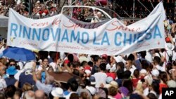 Pope Francis is driven through the crowd as a large banner reading "Let's renew the church" is visible in the foreground, in Palermo, Italy, Sept. 15, 2018. Francis was paying tribute in Sicily to a priest who worked to keep youths away from the Mafia and was slain by mobsters.