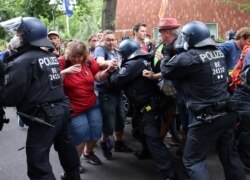 Police officers scuffle with demonstrators during a protest against government measures to curb the spread of COVID-19, in Berlin, Germany Aug. 1, 2021.