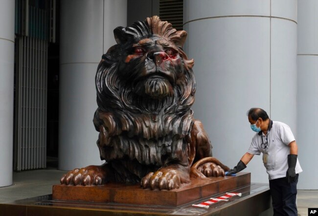 香港汇丰银行中环总部大厦前一名工人在清理“风水狮”遭示威者泼的红漆。(2020年1月2日)