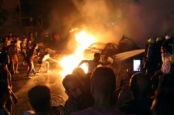 People extinguish a fire from a blast outside the National Cancer Institute, Cairo, Egypt Aug. 4, 2019.