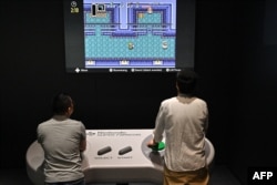 This photo taken on September 24, 2024 shows visitors interacting with a game during a media preview of the new Nintendo Museum, located inside a renovated old factory, in the suburbs of Kyoto. (Photo by Richard A. Brooks / AFP)