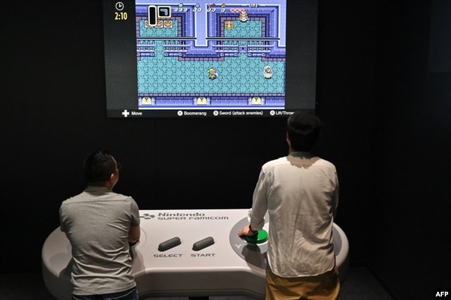 This photo taken on September 24, 2024 shows visitors interacting with a game during a media preview of the new Nintendo Museum, located inside a renovated old factory, in the suburbs of Kyoto. (Photo by Richard A. Brooks / AFP)