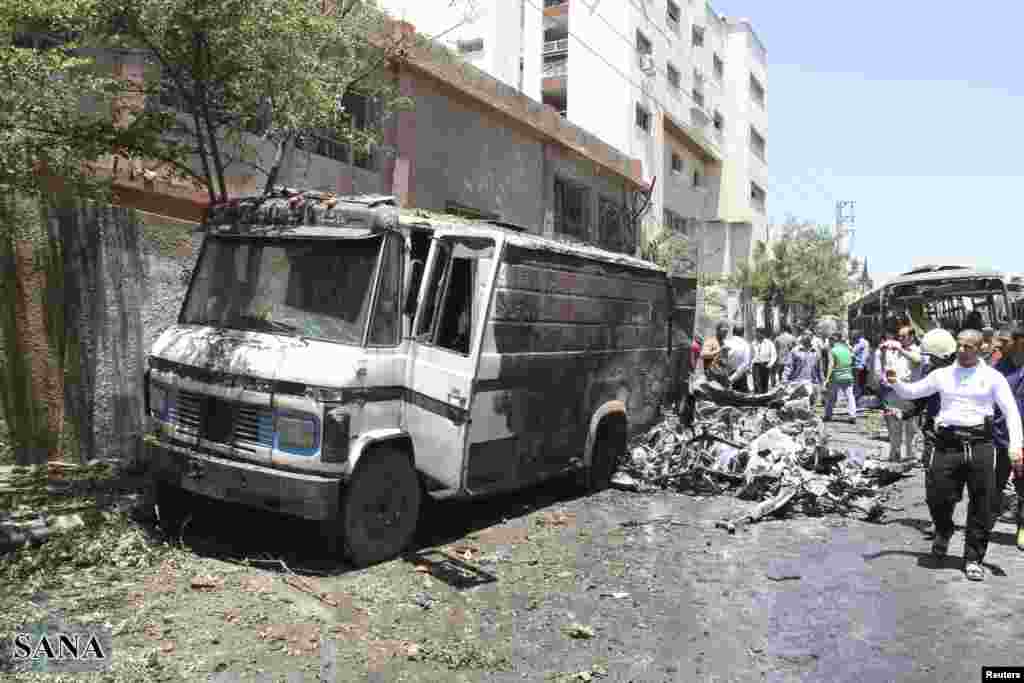 Residents and security personnel gather at the site of an explosion in a Damascus suburb in this handout released by Syria&#39;s national news agency SANA, June 8, 2012. 