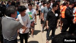 FILE - Chinese citizens who have been arrested over an alleged internet scam line up before a deporting back to China, at the international airport in Phnom Penh, Cambodia.