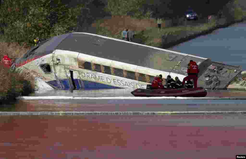 French fire brigade members work at the scene of the wreckage of a test TGV train that derailed and crashed, killing at least ten people, in a canal outside Eckwersheim near Strasbourg, eastern France.