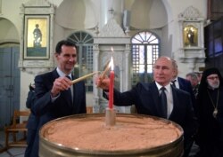 FILE - Russian President Vladimir Putin and his Syrian counterpart Bashar al-Assad visit an Orthodox Christian cathedral in Damascus, Syria, Jan. 7, 2020.