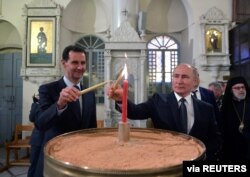 FILE - Russian President Vladimir Putin and his Syrian counterpart Bashar al-Assad visit an Orthodox Christian cathedral in Damascus, Syria, Jan. 7, 2020.