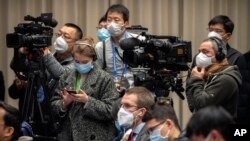 Journalists wearing face masks attend an official press conference about a virus outbreak at the State Council Information Office in Beijing, Sunday, Jan. 26, 2020. The new virus accelerated its spread in China, and the U.S. Consulate in the…