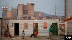 People sitting outside their shacks in the Nkaneng shantytown next to the platinum mine, run by British company Lonmin, in Marikana. South Africa, July 9, 2913.