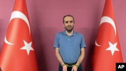 Selahattin Gulen, a nephew of U.S.-based Muslim cleric Fethullah Gulen, stands between Turkish flags in this photo provided by Turkish intelligence service, May 31, 2021, in Ankara, Turkey.