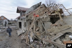 A villager passes by debris of private houses ruined in Russia's night rocket attack in a village, in Zolochevsky district in the Lviv region, Ukraine, Thursday, March 9, 2023. (AP Photo/Mykola Tys)