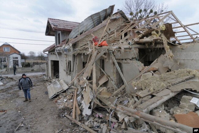 A villager passes by debris of private houses ruined in Russia's night rocket attack in a village, in Zolochevsky district in the Lviv region, Ukraine, Thursday, March 9, 2023. (AP Photo/Mykola Tys)