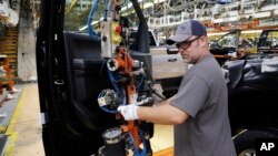 FILE - An worker installs the front doors on a 2018 Ford F-150 truck being assembled at the Ford Rouge assembly plant, in Dearborn, Michigan, Sept. 27, 2018.