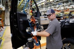 FILE - A worker installs the front doors on a Ford F-150 truck being assembled at the Ford Rouge assembly plant, in Dearborn, Michigan, Sept. 27, 2018.