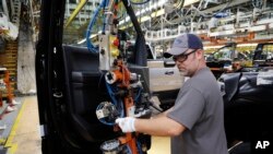 FILE - An worker installs the front doors on a 2018 Ford F-150 truck being assembled at the Ford Rouge assembly plant, in Dearborn, Michigan, Sept. 27, 2018.