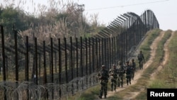 FILE - Indian Border Security Force (BSF) soldiers patrol the fenced border with Pakistan at Bobiya village in Hira Nagar sector, about 80 km (50 miles) from Jammu, Dec. 6, 2013.