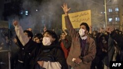 FILE - Protesters chant slogans and hold a placard reading in Farsi "Your mistake was unintentional, your lie was intentional," during an anti-government rally outside Amir Kabir University, in Tehran, Iran, Jan. 11, 2020.