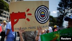 FILE - An anti-government doctor holds a placard during a march to demand medical supplies for hospitals in Caracas, March 10, 2014. 