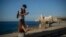 A youth uses his smartphone as he and a friend walk along the Malecon seawall in Havana, Cuba, Friday, Nov. 25, 2022. 